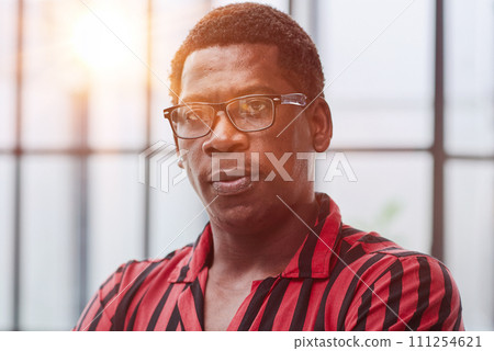 Portrait of confident african american businessman with glasses standing in office with crossed arms Portrait of confident african american businessman with glasses standing in office with crossed arms 111254621