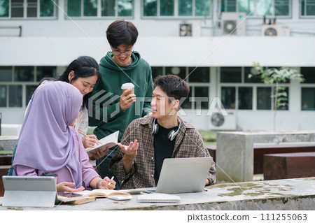 Multi ethnic group of university students brainstorming together outdoors at campus. 111255063