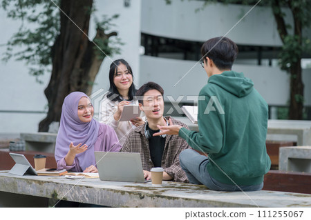 Diverse group of university students brainstorming together outdoors at campus. 111255067