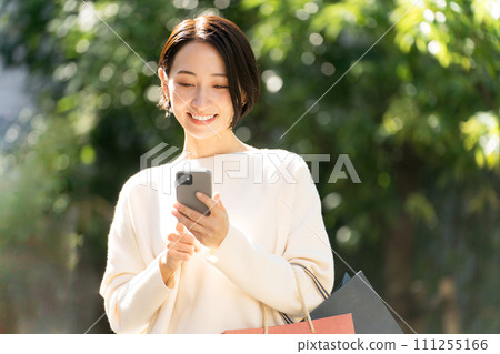 一位女士帶著智慧型手機購物回來 一位女士帶著智慧型手機購物回來 111255166