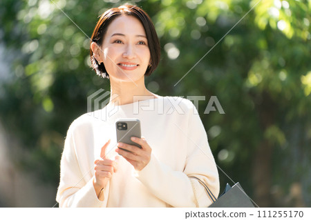 A woman returning from shopping with a smartphone 111255170