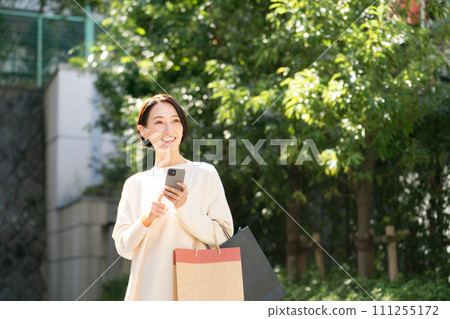 一位女士帶著智慧型手機購物回來 111255172