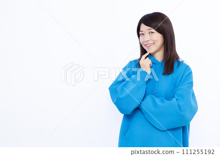 A woman in her 40s wearing a hoodie smiling and thinking 111255192