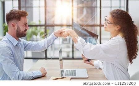 woman doctor holding an x-ray in her hands shakes hands with a patient 111255200