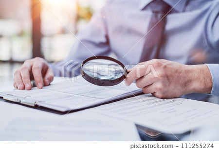 Businessman looking through a magnifying glass to documents 111255274