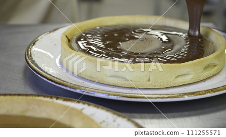 Chocolate pouring on piece of delicious freshly baked cakes 111255571