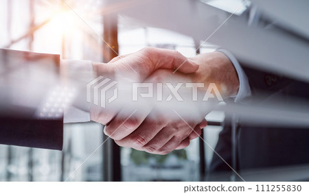 executives shaking hands in front of their manager and a colleague executives shaking hands in front of their manager and a colleague 111255830