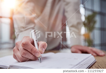 Businessman writes with a pen in diary sunny office, business and education concept. Close up 111255927
