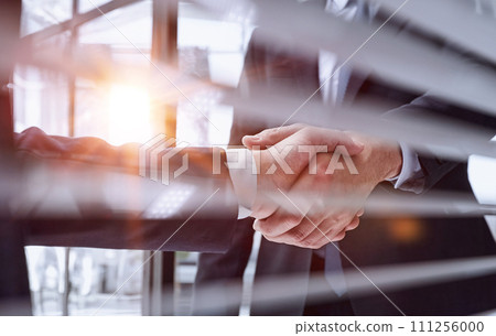 executives shaking hands in front of their manager and a colleague executives shaking hands in front of their manager and a colleague 111256000