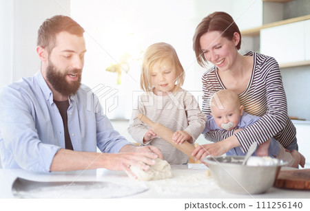 Young parents playing with children in the kitchen 111256140