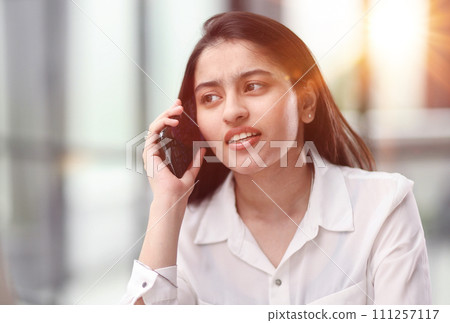 Portrait of young business woman with glasses ofand talking on mobile phone Portrait of young business woman with glasses ofand talking on mobile phone 111257117