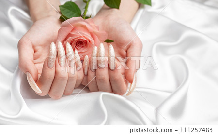 Female Hands on a white silk background with beautiful pearl manicure.Hands on a brown background and beautiful pearl manicure Female Hands on a white silk background with beautiful pearl manicure.Hands on a brown background and beautiful pearl manicure 111257483