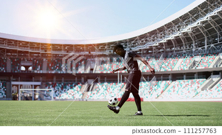 African American man playing football on the stadium field. A man runs with a soccer ball across the field. 111257763