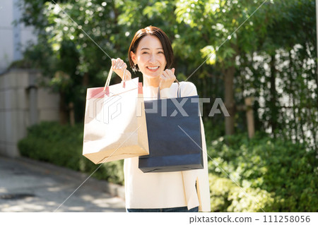 woman holding shopping bags in both hands woman holding shopping bags in both hands 111258056