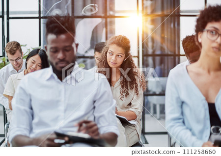 Multi-ethnic group of people while answering questions during training seminar or business conference in office, copy space 111258660