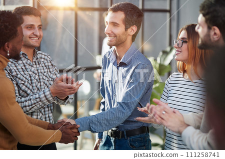 Smiling businessman standing greeting partner with handshake. Smiling businessman standing greeting partner with handshake. 111258741