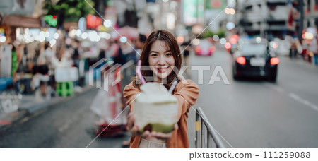 Young asian woman traveller standing and drinking coconut water Young asian woman traveller standing and drinking coconut water 111259088