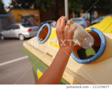 woman throwing plastic bottle Recycling bin stand on european street. Waste separation rubbish before drop to garbage bin to save world, environment care. Pollution trash recycling management concept 111259677
