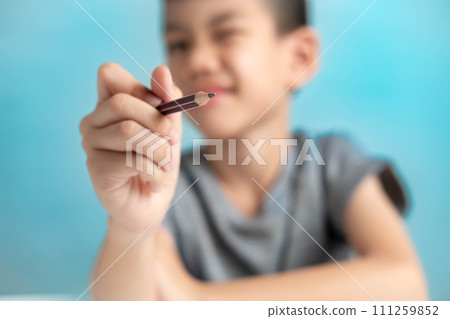 Asian Boy holding a pencil drawing in the air, imagination concept of a child on a blue background 111259852