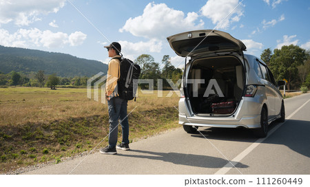 Man carrying backpack standing on countryside and looking at beautiful mountain view. Local solo travel on weekends concept 111260449