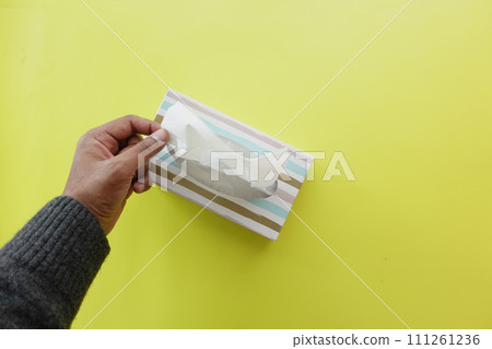 hand pull out a piece of tissue from tissue paper box hand pull out a piece of tissue from tissue paper box 111261236
