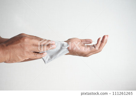 man disinfecting his hands with a wet wipe. 111261265
