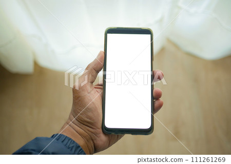 holding smart phone with white screen and home interior decoration on table  111261269