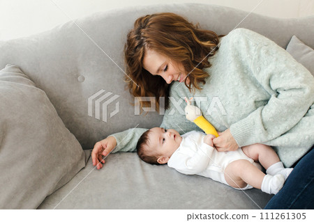 Happy mother resting on sofa with baby Happy mother resting on sofa with baby 111261305