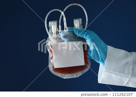 Bag with donor blood in gloved hand on blue background 111262107