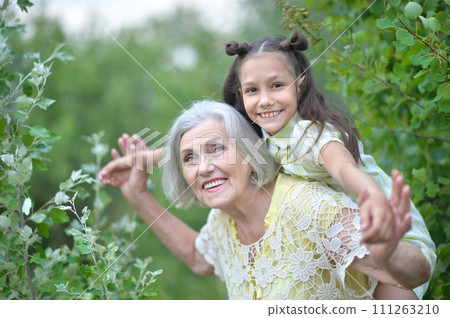 Portrait of happy grandmother and granddaughter in park Portrait of happy grandmother and granddaughter in park 111263210