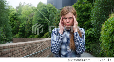 Girl with a headache on the street 111263913