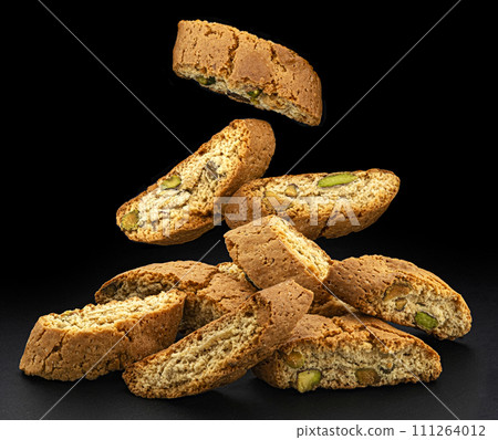 Falling cantuccini biscuits, Italian almond cookies on black background Falling cantuccini biscuits, Italian almond cookies on black background 111264012