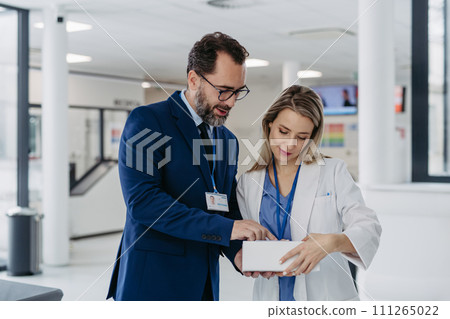 Pharmaceutical sales representative talking with doctor in medical building. Ambitious male sales representative presenting new medication. 111265022