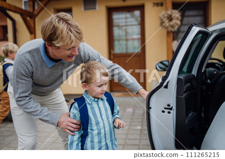 School boy getting into the car. Father taking son to school before going to work. School boy getting into the car. Father taking son to school before going to work. 111265215