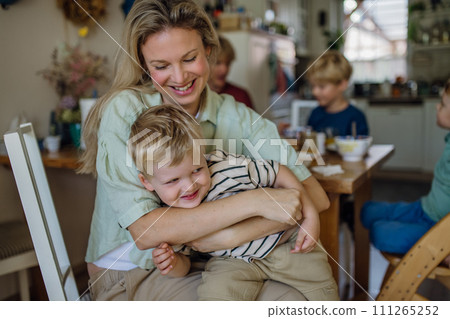 Mother feeding little baby with breakfast in home kitchen, having fun, laughing. 111265252