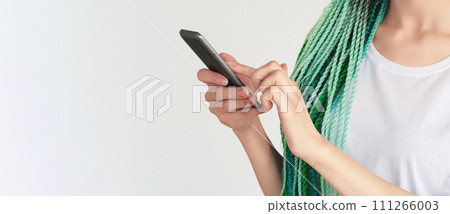 Creative hairstyle. Mobile chat. Unrecognizable woman with mint blue hair braids using smartphone browsing internet isolated on white copy space background. Creative hairstyle. Mobile chat. Unrecognizable woman with mint blue hair braids using smartphone browsing internet isolated on white copy space background. 111266003