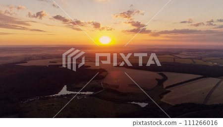 Aerial countryside view. Sunset landscape. Green field in red orange color sun light evening nature scenery skyline background drone shot. Aerial countryside view. Sunset landscape. Green field in red orange color sun light evening nature scenery skyline background drone shot. 111266016