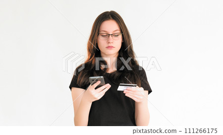 Bank scam. Transaction risk. Personal data security. Confused woman using phone credit card information for Internet payment isolated on white copy space background. Bank scam. Transaction risk. Personal data security. Confused woman using phone credit card information for Internet payment isolated on white copy space background. 111266175