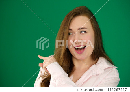 woman advertises something at mock-up blank white copy space on side up background pointing indicates with index finger woman advertises something at mock-up blank white copy space on side up background pointing indicates with index finger 111267317