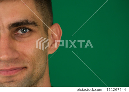 Close up of handsome man's half face isolated over green background. Portrait of attractive hipster standing against white background. Masculinity and charisma and male beauty concepts 111267344