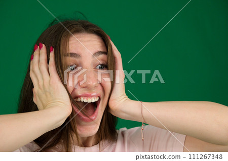 Young woman is looking surprised isolated on green background Young woman is looking surprised isolated on green background 111267348