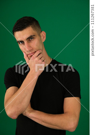 young guy lost in thought, supports his head with his hand, squints his eyes, gazes intently, black T-shirt, light stubble, macho, ponders thoughts, emotions of a handsome man young guy lost in thought, supports his head with his hand, squints his eyes, gazes intently, black T-shirt, light stubble, macho, ponders thoughts, emotions of a handsome man 111267381