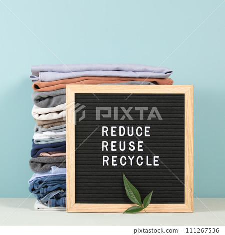 Black letter box and stack of folded clothes on blue background, reduce,reuse,recycle quote 111267536