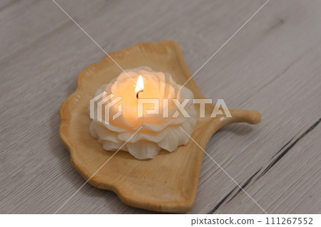lit burning candle in the form of a rose with wax petals against background of massage candles spa salon interior beautifully burning fire relaxation pleasant time beauty self care massage treatments 111267552