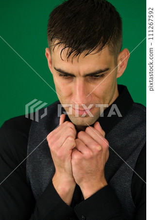 young man in a dark shirt and gray vest on a green background chromakey freeze snuggle worries boredom 111267592