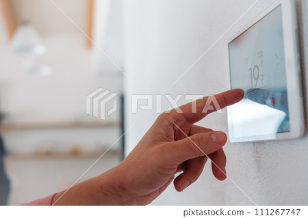 Close up of smart thermostat, adjusting, lowering heating temperature at home. Concept of sustainable, efficient, smart technology in home heating and thermostats. 111267747
