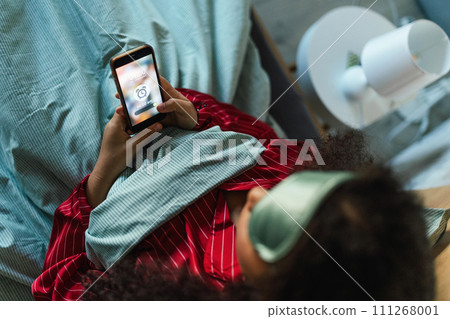 Woman setting alarm before going to sleep. Concept of sleep routine. Insomnia a sleep problems among adults. 111268001