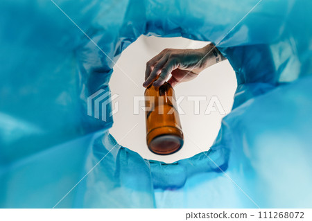 Man throwing glass bottle into recycling bin. Empty alcohol bottle, throwing, New Year's resolutions, drink less alcohol healthy lifestyle without alcoholic drinks. 111268072