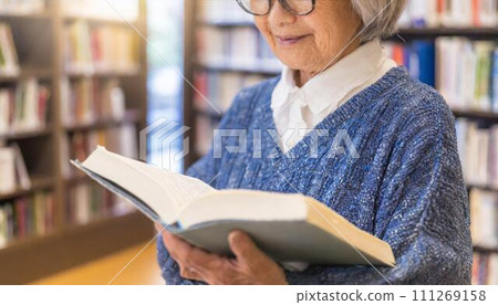 Senior woman reading a book in the library 111269158