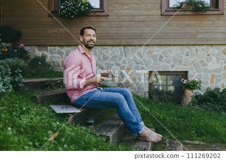 Low angle shot of man working outdoors in the garden, eating lunch, sandwich. Businessman working remotely from homeoffice, thinking about new business or creative idea. 111269202